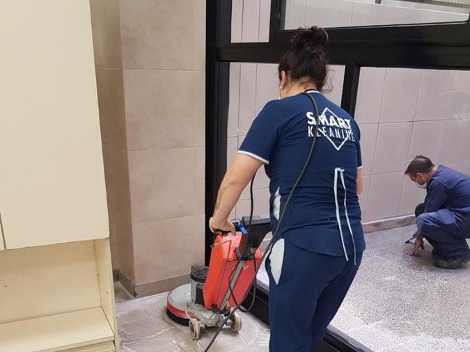 Operaria con uniforme limpiando un piso con una máquina
