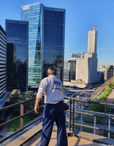 limpieza-consorcios Operario con buzo de trabajo en una terraza, frente a torres de oficinas