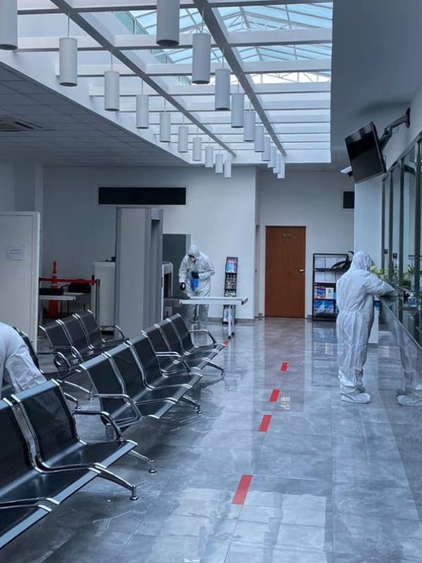 desinfeccion Personal con trajes de protección limpiando asientos y mostradores en una sala de espera